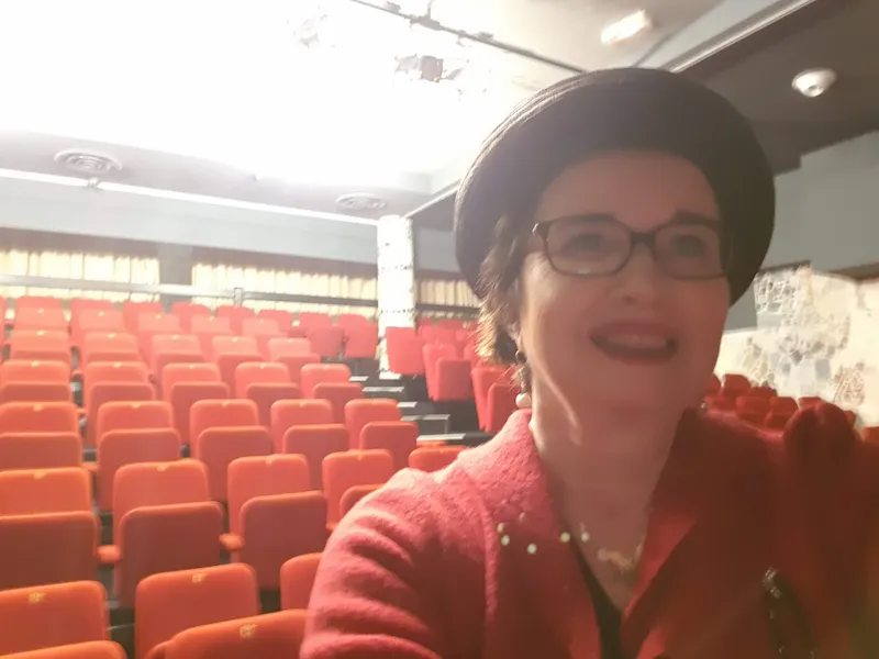 Selfie de Sabine Miniconi, avec en fond la salle du théâtre Le passage vers les étoiles